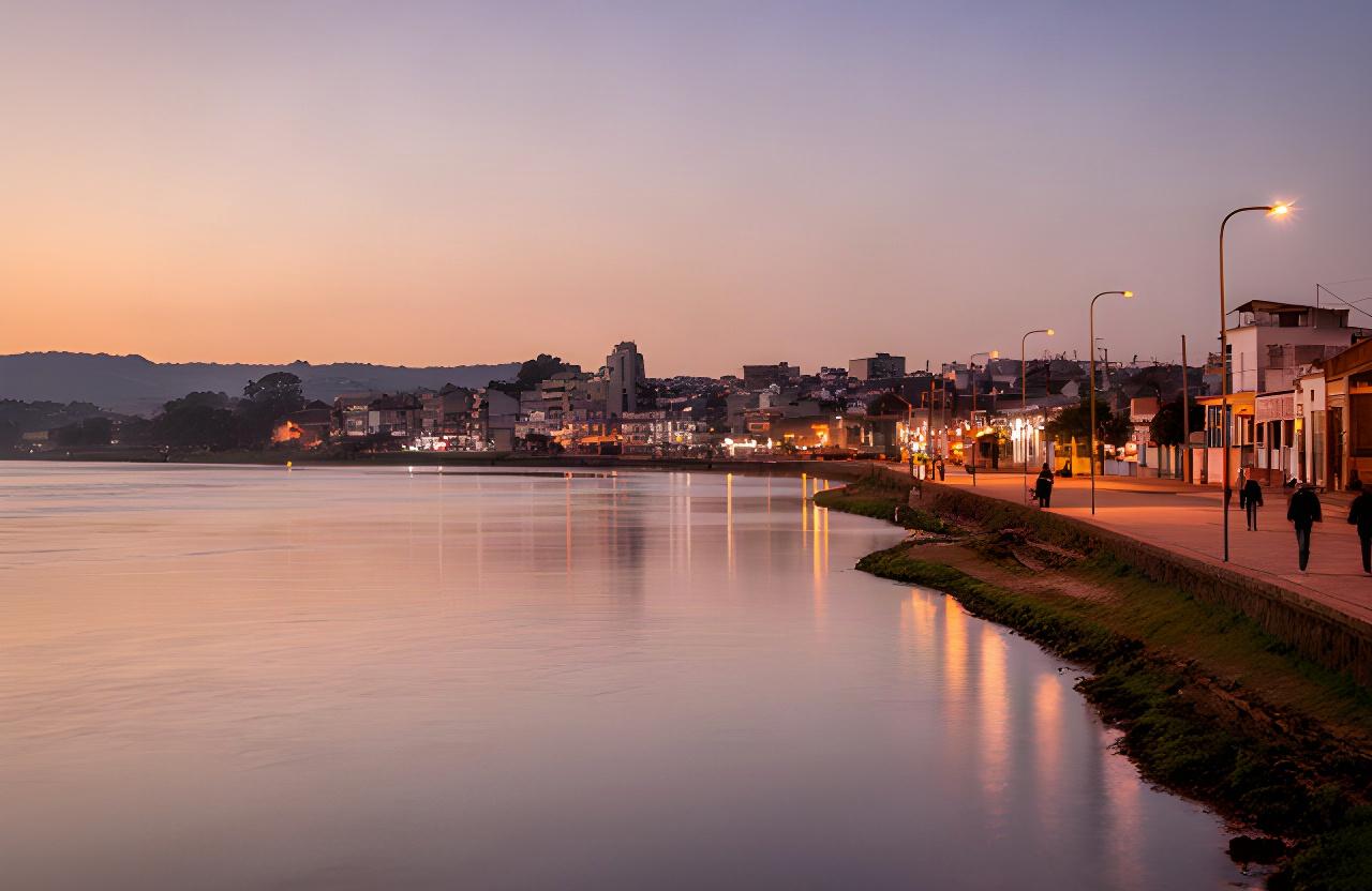 Rambla de Juan Lacaze al atardecer, con el río y las luces de la ciudad